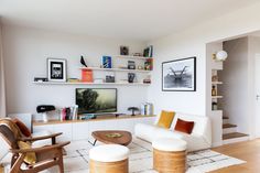 a living room filled with furniture and a flat screen tv on top of a wooden shelf