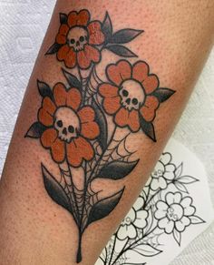 a woman's leg with flowers on it and a skull in the middle,