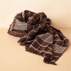 a brown and white checkered scarf sitting on top of a table next to a wall