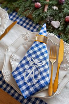 a blue and white place setting with silverware, napkins, and gold forks