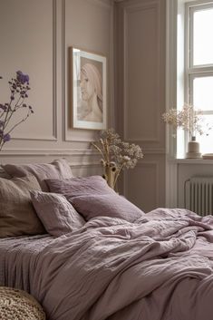 a bed with purple sheets and pillows next to a window in a room filled with flowers