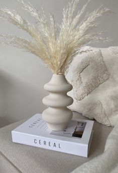 a white vase sitting on top of a book