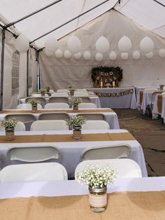 tables and chairs are set up in a tent with white linens on the ceiling