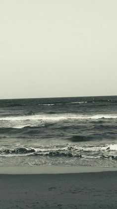 a person walking on the beach carrying a surfboard