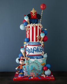 a three tiered cake decorated with balloons and mickey mouses is on top of a table