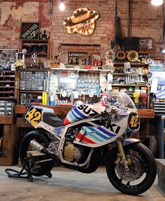 a motorcycle parked inside of a garage next to a wall with signs on it and lights hanging from the ceiling