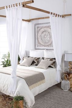 a bed with white drapes and pillows in a bedroom