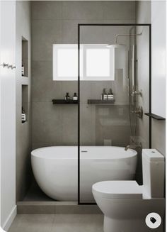 a white bath tub sitting next to a toilet in a bathroom under a light fixture