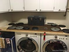 a washer and dryer in a small room with white cupboards on the wall