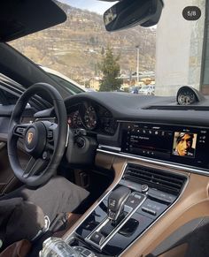 the interior of a luxury car with dashboard and steering wheel controls in front of a mountain view