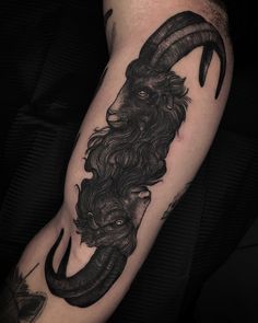 a man's arm with a goat head and horns on it, done in black ink