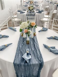 the table is set with blue and white linens, silver napkins, and flowers