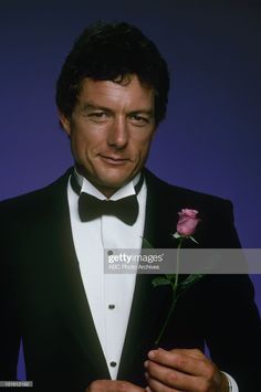 a man in a tuxedo holding a rose