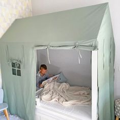 a little boy sitting on top of a bed under a tent