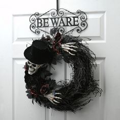 a skeleton wreath on the front door of a house with beware written on it