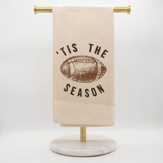 a tea towel with the words tis the season on it hanging from a gold metal holder