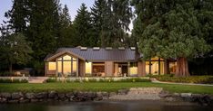 a house sitting on top of a lush green field next to a lake and forest