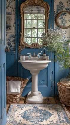 a bathroom with blue and white wallpaper, a mirror, sink and wicker baskets on the floor