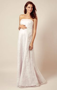 a pregnant woman in a white gown posing for the camera with her hands on her stomach