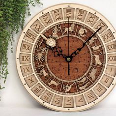 a wooden clock with animals and zodiac signs on the face next to a potted plant