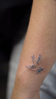 a small tattoo on the arm of a woman's left arm with blue ink