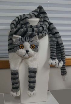 a knitted gray and white cat hat on top of a mannequin's head