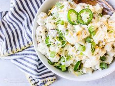 a white bowl filled with potato salad on top of a blue and white striped towel