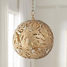 a wooden ball hanging from a chain in a room with white walls and windows,