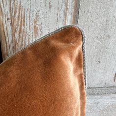 an orange velvet pillow sitting on top of a wooden floor next to a white door