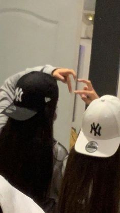 two people in front of a mirror with one pointing at the other's hat