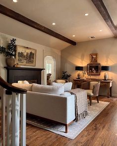 a living room filled with furniture and a fire place next to a wooden floored staircase