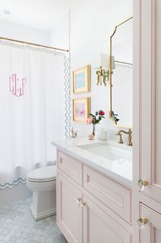 a bathroom with pink and white decor on the vanity, shower curtain, and toilet