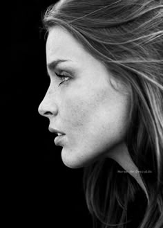 a black and white photo of a woman's face with hair blowing in the wind