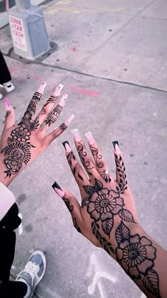 two hands with henna tattoos on their palms and one hand holding something in the air