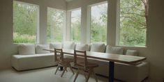 a living room filled with white furniture and large windows overlooking the trees in the distance