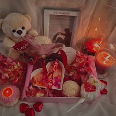 a teddy bear sitting on top of a bed next to valentine's day treats