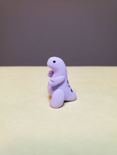 a small purple toy sitting on top of a white table next to a gray wall