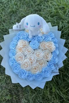 a stuffed animal sitting on top of a blue and white rose covered cake in the shape of a heart