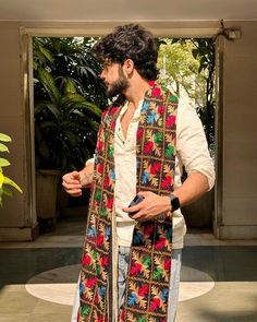 a man standing in front of a doorway wearing a multicolored scarf