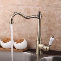 a faucet that is running water in a kitchen sink with soap dispensers