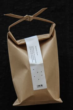 a brown paper bag with a note attached to the handle on a black tablecloth