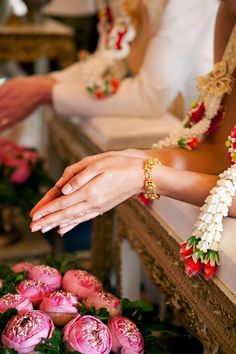 two brides holding hands in front of pink flowers and greenery on the table