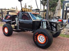 an off - road vehicle with orange wheels parked on the side of a brick walkway