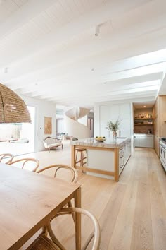 an open kitchen and dining room with wood flooring, white walls and ceiling beams