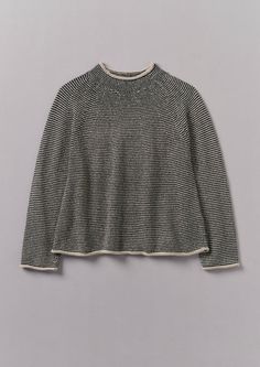 a black and white striped sweater hanging on a gray wall, with the top half turned down