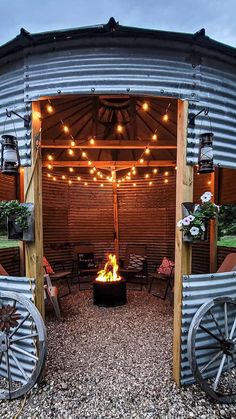 an outdoor fire pit in the middle of a gravel area with lights strung over it