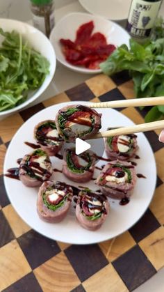 a person holding chopsticks over a plate of food on a checkered table