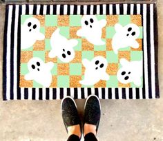 a person standing in front of a door mat with ghost faces on it and black and white stripes