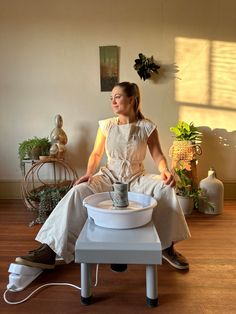 a woman sitting on top of a table with a potted plant in her lap