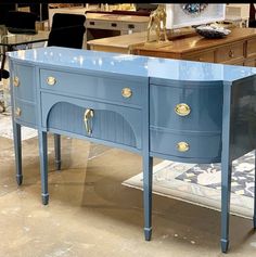 a blue table with two drawers and gold pulls on it in a room filled with furniture